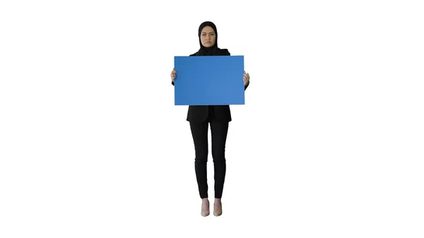 Komoly arab nő hidzsábban, üres kék poszterrel a kezében és nézelődve. — Stock Fotó