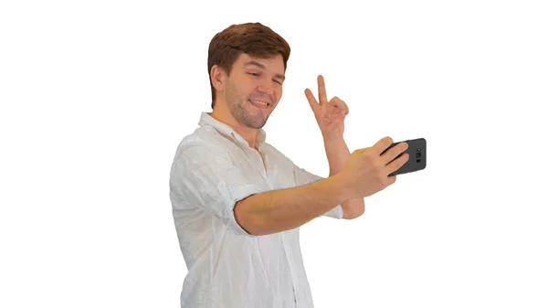 Young man in casual white shirt taking selfies on his phone on w — Stock Photo, Image