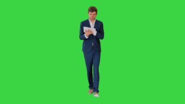 Gülümseyen işadamı yeşil ekranda yürürken dijital tablet kullanıyor, Chroma Key.