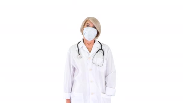 Ανώτερος γυναίκα γιατρός κατά τη διάρκεια μιας πανδημίας covid-19 coronavirus βγάζει προστατευτική μάσκα σε λευκό φόντο. — Αρχείο Βίντεο
