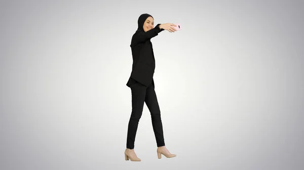 Улыбающаяся арабская женщина в хиджабе делает селфи на свой мобильный телефон — стоковое фото
