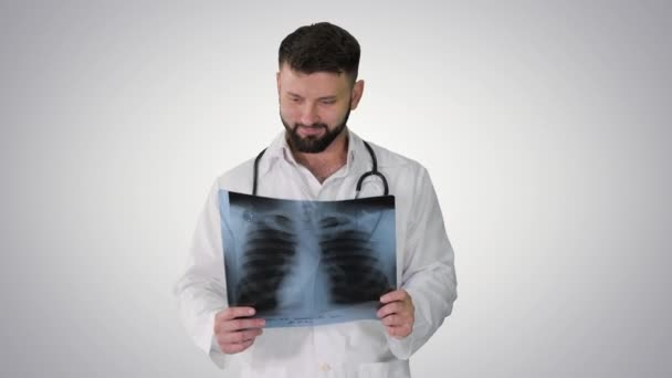 Médico caminando y mirando la imagen de rayos X de los pulmones en el fondo del gradiente. — Vídeos de Stock