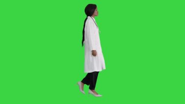 Üzgün Afrikalı Amerikalı kadın doktor elini cebine atarak yeşil ekranda yürüyor, Chroma Key.