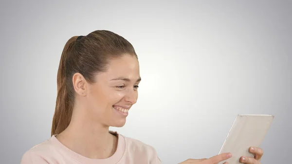Jovem mulher alegre está usando tablet no fundo gradiente. — Fotografia de Stock