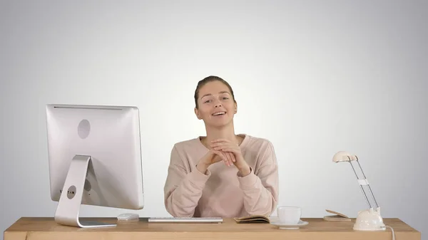 Sorridente donna millenaria seduta alla scrivania e parlare con le telecamere s — Foto Stock