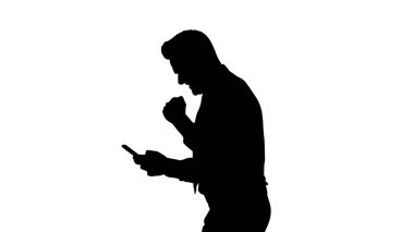 Siluet Mutlu iş adamı cep telefonu kullanarak karede yürüyor ve sonra kazanan hareketi yapıyor..