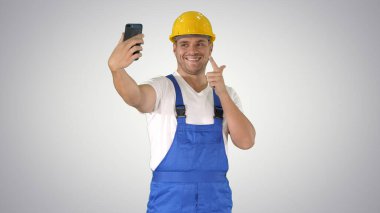 Gülümseyen yakışıklı inşaatçı cep telefonuyla selfie çekiyor.