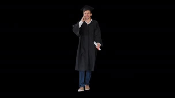 Чоловічий випускник з сукні та дошки, розмовляючи по телефону зі своїм дипломом Альфа Канал. — стокове відео