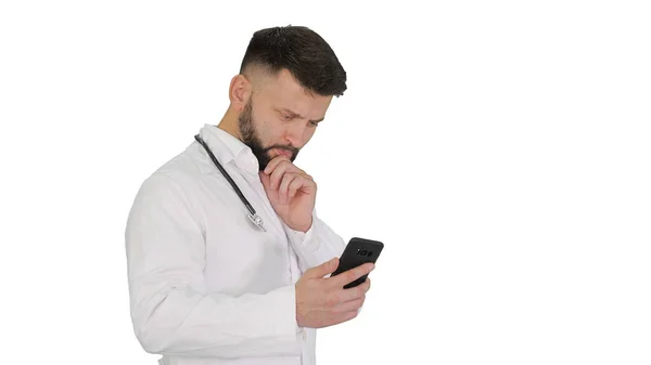 Beyaz üniformalı bir erkek doktor. Yürüyor ve akıllı telefon kullanıyor. — Stok fotoğraf