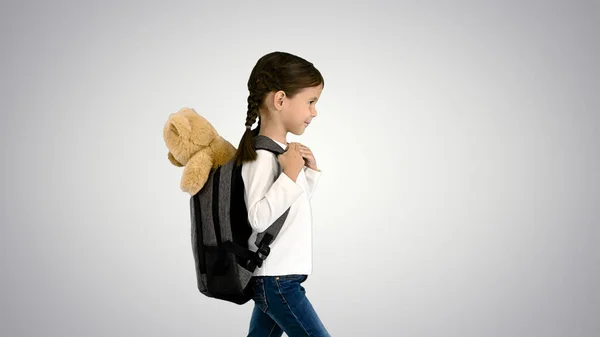 귀여운 여자 애가 학교에 걸어가고 있어요 테디 베어가 강아지를 안고 있고 — 스톡 사진