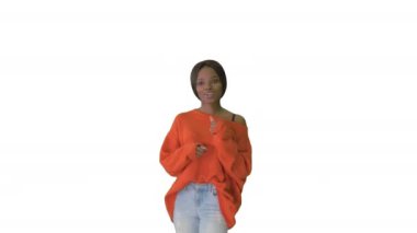 Parlak kazak ve kot pantolon giyen neşeli Afrikalı Amerikalı kadın beyaz arka planda kameraya konuşuyor..