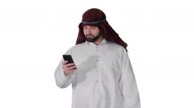 Arap adam internette akıllı telefon sörfü yapıyor ya da beyaz arka planda yürürken mesajlaşıyor..