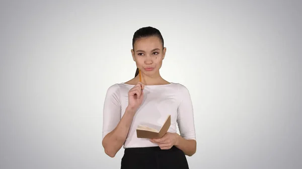 Mujer joven haciendo notas mientras camina sobre fondo degradado. — Foto de Stock