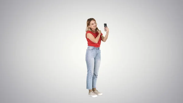 Donna bionda che si pavoneggia davanti allo smartphone su gradiente bac — Foto Stock