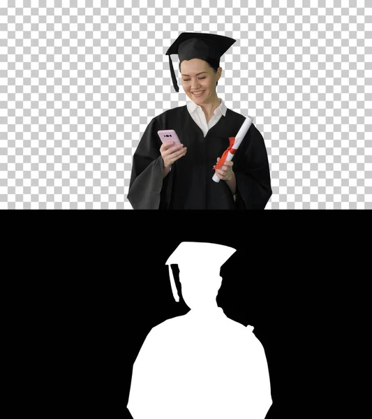 Šťastná žena absolvent držící diplom a textování na telefonu, — Stock fotografie