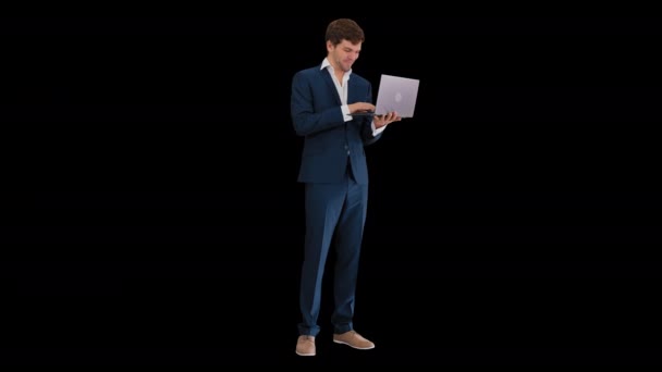 Улыбающийся молодой бизнесмен с помощью ноутбука, стоя, Альфа-канал — стоковое видео