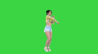 Kare gömlekli ve kot şortlu kız, spor ayakkabılı, yeşil ekranda dans eden, Chroma Key.