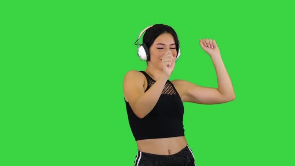 Очаровательная девушка в шортах и наушниках танцует на зеленом экране, Chroma Key. — стоковое видео