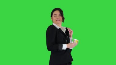 Kendinden emin ve mutlu genç iş kadını cebine para koyup yeşil ekranda dans ediyor, Chroma Key..