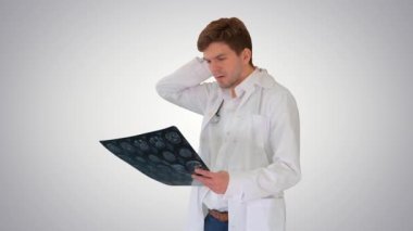 Sinirli erkek doktor gradyan arkaplanda beynin bilgisayarlı tomografi taramasını inceliyor..