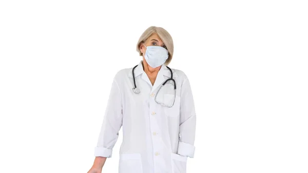 Senior läkare sätta på medicinsk mask tittar på kameran på w — Stockfoto