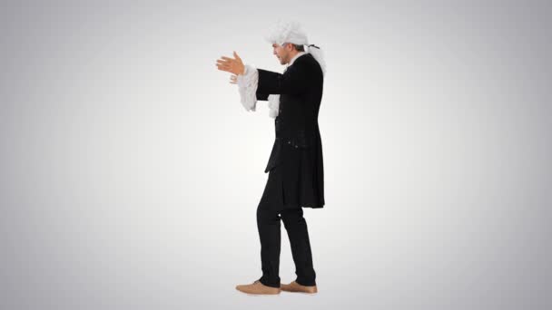 Człowiek ubrany jak Wolfgang Amadeus Mozart dyrygujący orkiestrą na gradientowym tle. — Wideo stockowe