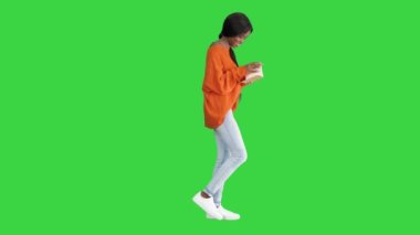 Güzel Afro-Amerikan kadın, parlak kazaklı, not defterini okuyor ve yeşil ekranda gülüyor, Chroma Key..