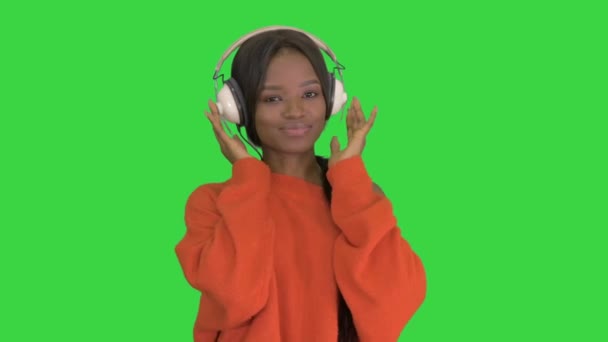 Молода афроамериканська жінка з навушниками, яка слухає музику на "Зеленому екрані", Chroma Key. — стокове відео