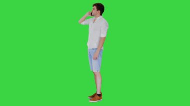 Mutlu genç adam cep telefonuyla konuşuyor ve yeşil ekranda gülümsüyor, Chroma Key.