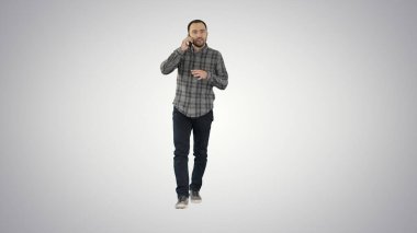 Yürüyen adam telefonda konuşuyor ve sırtına gülümsüyor.