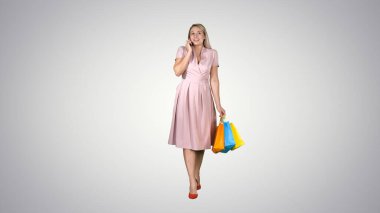 Genç bir kadın alışveriş yapıyor ve yürürken telefonla konuşuyor.