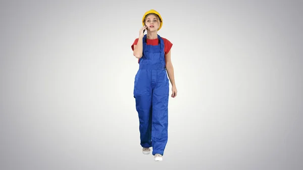 Female construction woman making a call on gradient background.