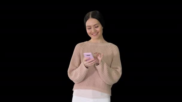 Sorrindo jovem mulher mensagens de texto em seu telefone celular e rindo, Alpha Channel — Vídeo de Stock