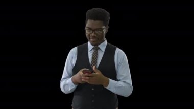 Alpha Channel 'da yürüyen ve mesajlaşan mutlu Afro-Amerikan iş adamı.