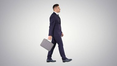 Takım elbiseli yakışıklı bir işadamı, Gradien 'de bir çantayla yürüyor.