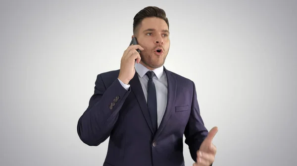 Serious worried businessman talking on cellphone on gradient bac — Stock Photo, Image
