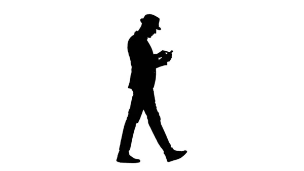 실루엣 (Silhouette): 걷는 동안 스마트폰을 사용하는 평범 한 산발적 인 남자. — 스톡 사진