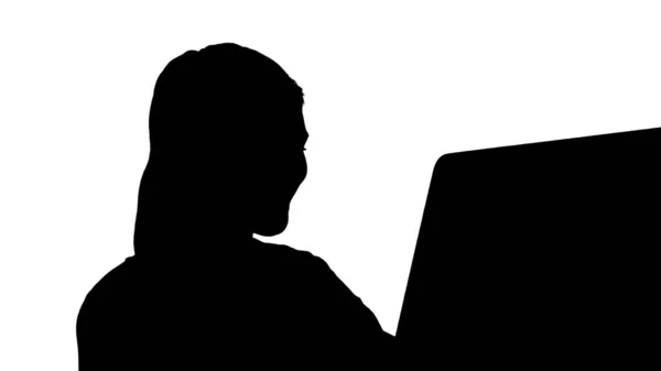 Silhouette Studentisches blondes Mädchen blickt auf Monitor des Computers und lächelt. — Stockfoto