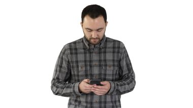 Genç adam yürüyor ve beyaz arka planda akıllı telefon kullanıyor..