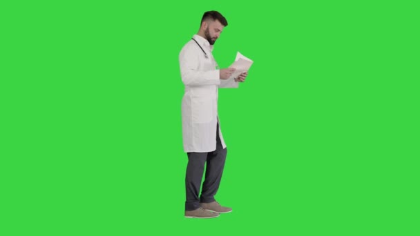 Άνδρας γιατρός περπάτημα και κοιτάζοντας καρδιογράφημα σε μια πράσινη οθόνη, Chroma Key. — Αρχείο Βίντεο
