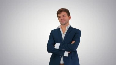 Yakışıklı genç işadamı kollarını kavuşturmuş, değişken arka planda güvenle gülümsüyor..