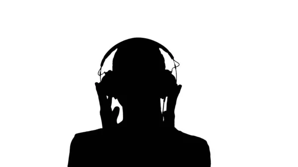 Silhouette Una joven escuchando música en auriculares. —  Fotos de Stock