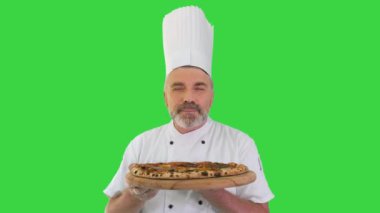 Gülümseyen şef lezzetli pizza kokusu alıyor ve yeşil ekranda reçel jesti yapıyor, Chroma Key.