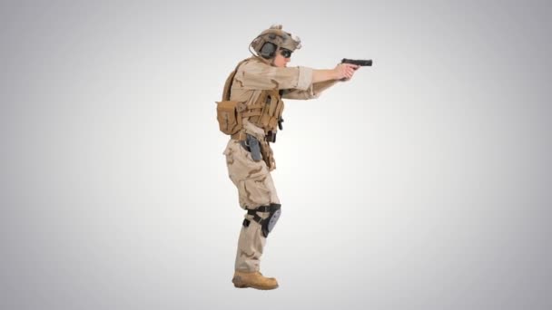Soldat armé en camouflage marchant et visant avec une arme de poing sur fond dégradé. — Video