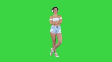 Kulaklık takan genç İspanyol kadın yeşil ekranda ciddi bir yüz düşünüyor, Chroma Key..