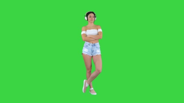 Ung latinamerikansk kvinna i hörlurar allvarligt ansikte tänker på en grön skärm, Chroma Key. — Stockvideo