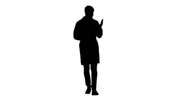 Silhouette Médecin d'âge moyen homme portant l'uniforme médical présentant et pointant avec la paume de la main regardant la caméra. — Photo