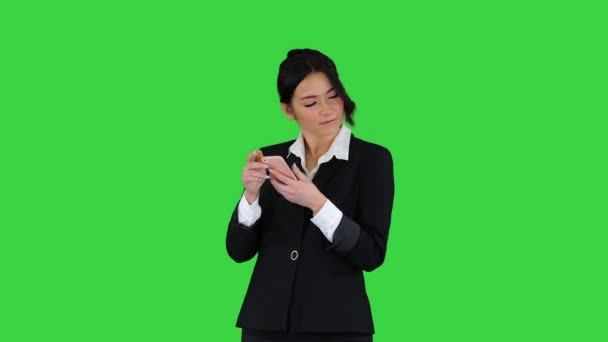 Junge Geschäftsfrau hört Musik am Telefon und tanzt dazu auf einem Green Screen, Chroma Key. — Stockvideo