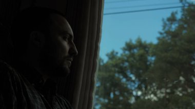 Üzgün genç adam trenin penceresinden bakıyor..