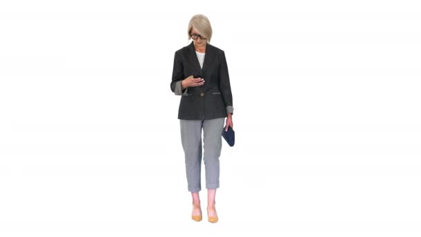 Intelligent eldre kvinne som bruker smarttelefon mens hun går på hvit bakgrunn. – stockvideo